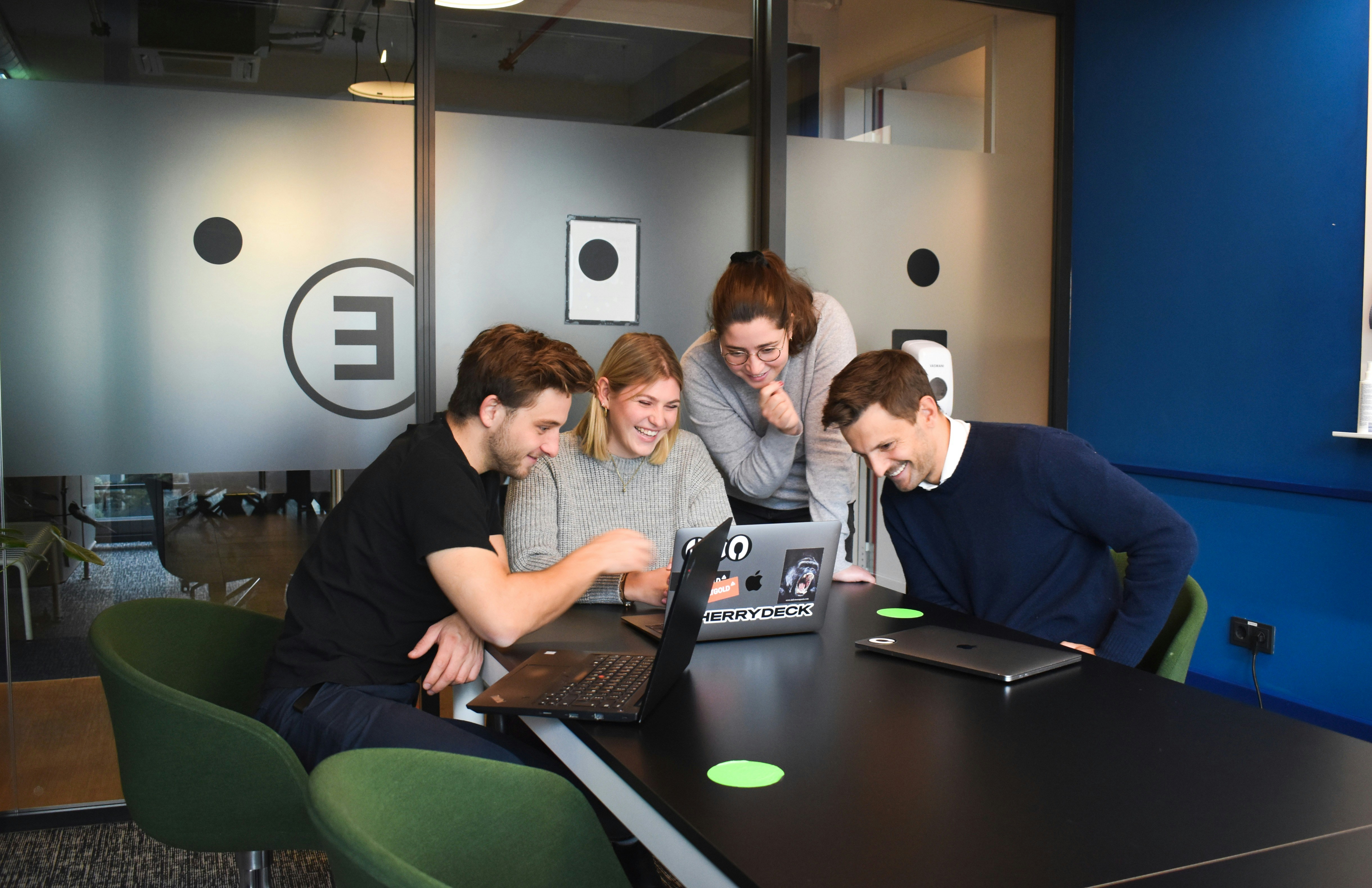 people sitting at a table looking at a laptop