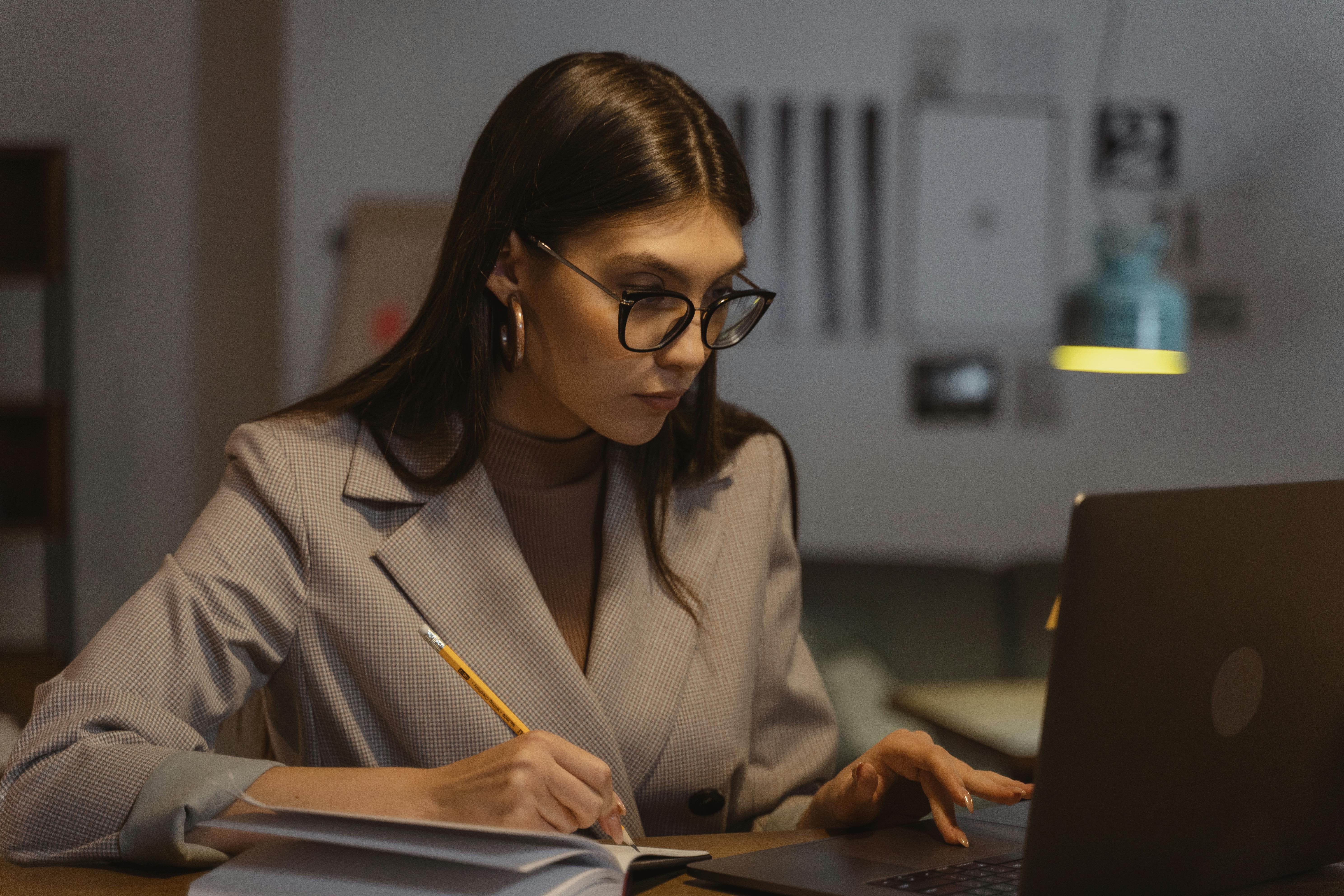 woman wearing glasses writing in a notebook